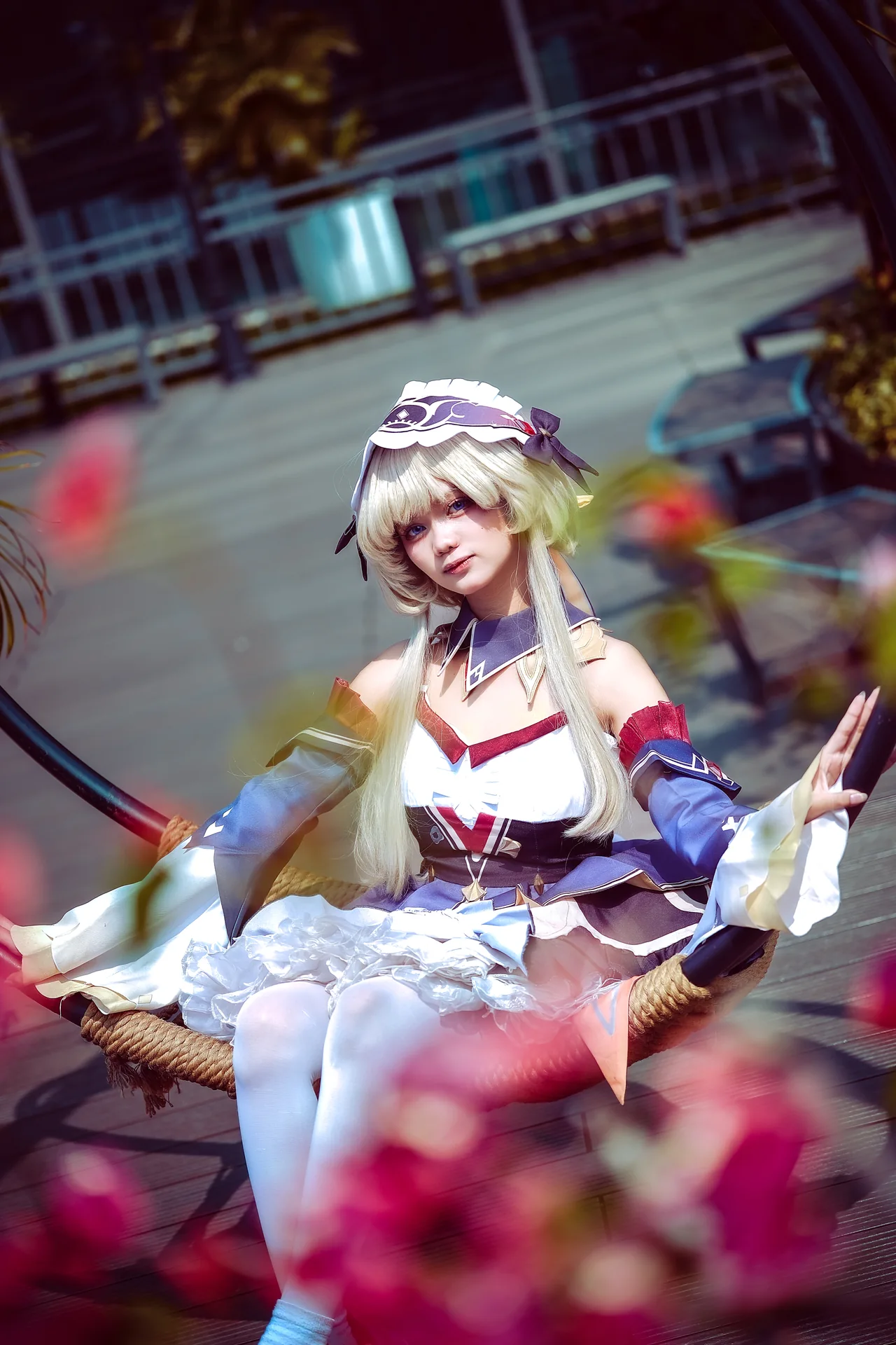 Blonde cosplayer framed by flowers on a circular swing