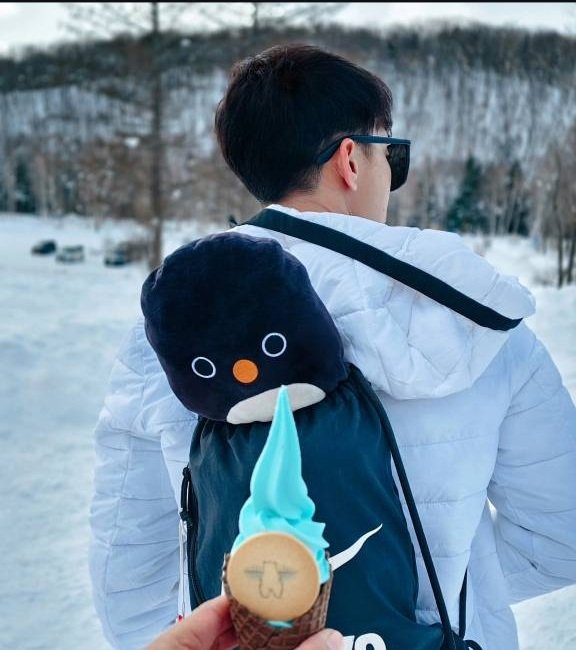 Nino in a white winter jacket carrying a penguin backpack